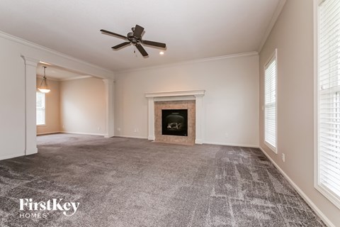 A spacious room with a fireplace and a ceiling fan.