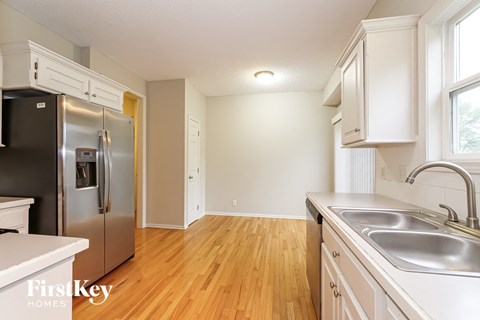 A kitchen with a stainless steel refrigerator and wooden floors.