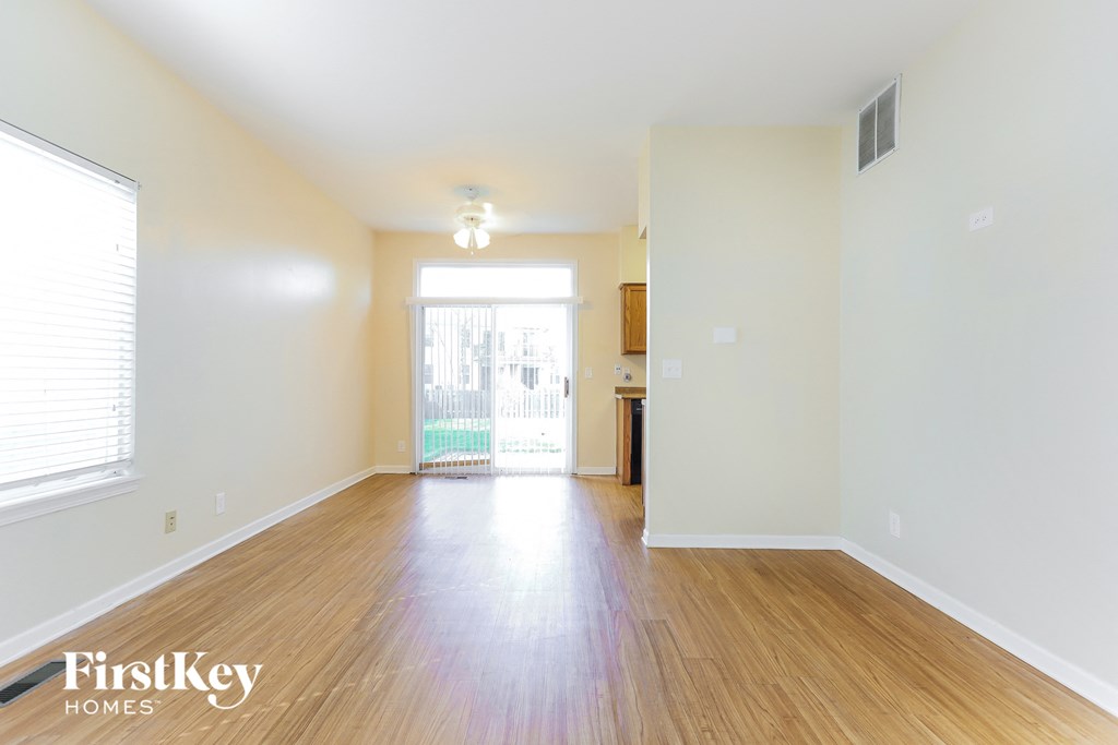 a spacious living room with hardwood flooring and a door to the kitchen