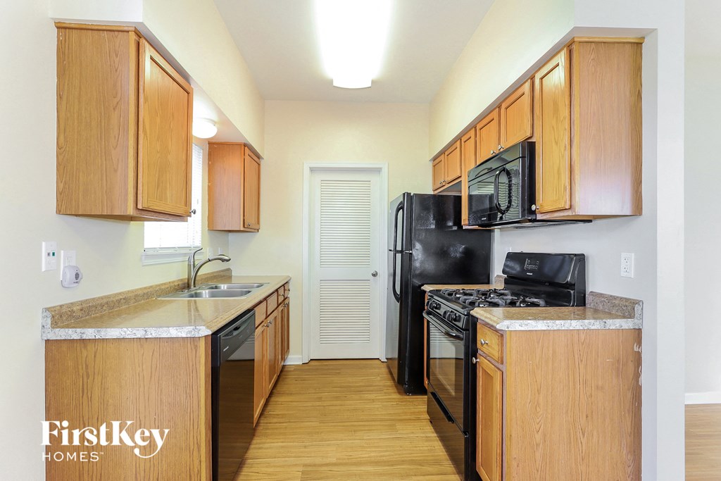 a kitchen with wood cabinets and black appliances and a black refrigerator