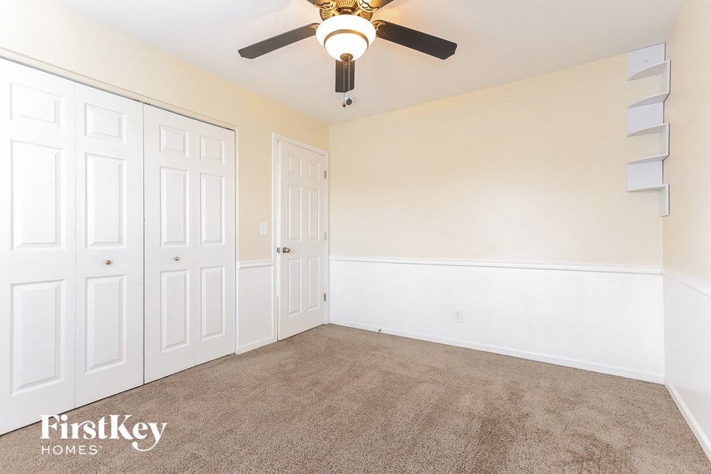 a bedroom with white walls and a ceiling fan