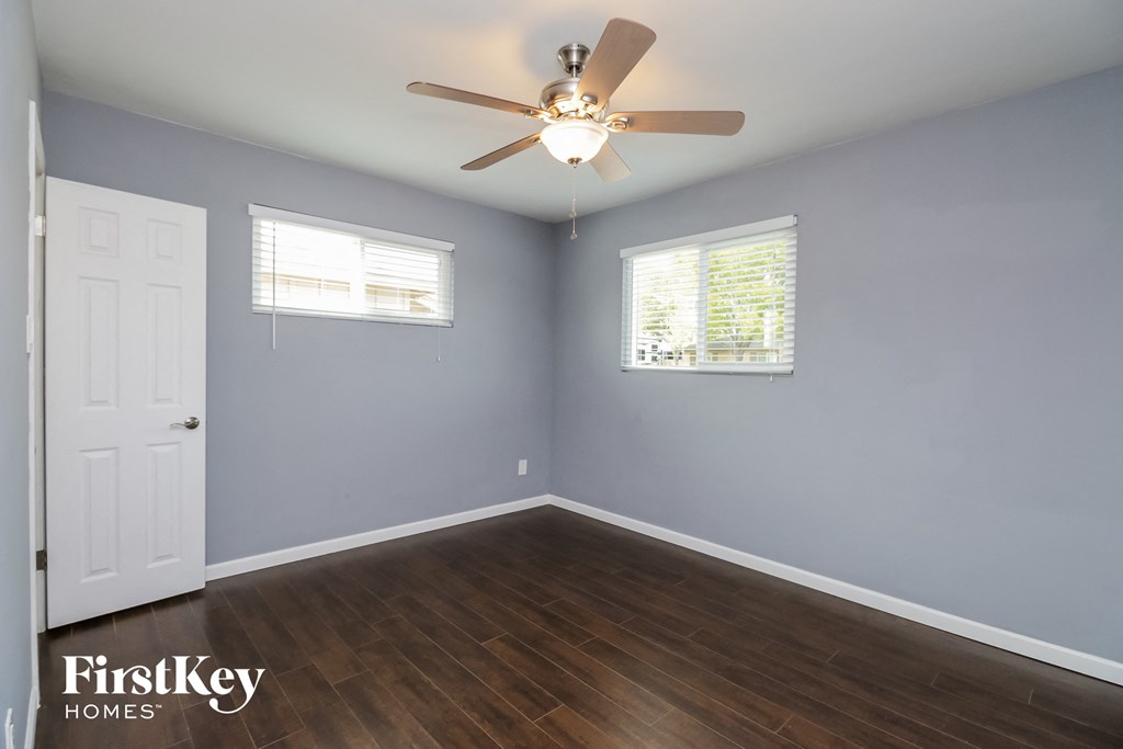 a bedroom with wood floors and a ceiling fan