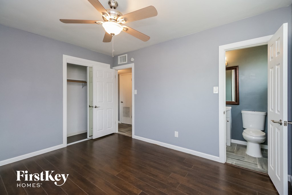 an empty room with a ceiling fan and a toilet