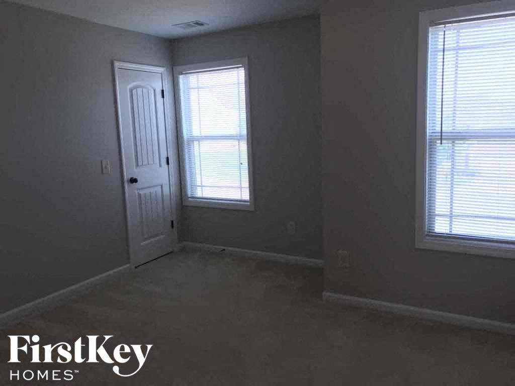 an empty room with a door and two windows