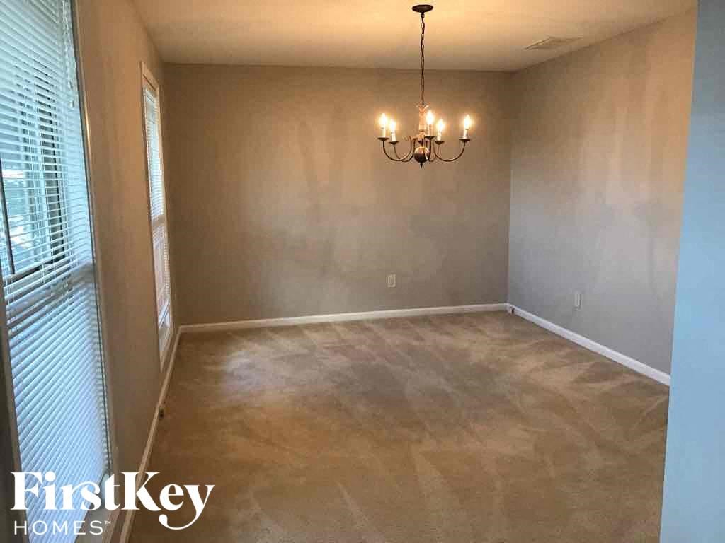 a empty dining room with a chandelier and a window