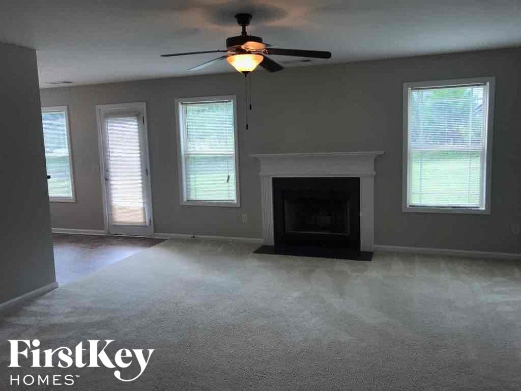 an empty living room with a ceiling fan and a fireplace