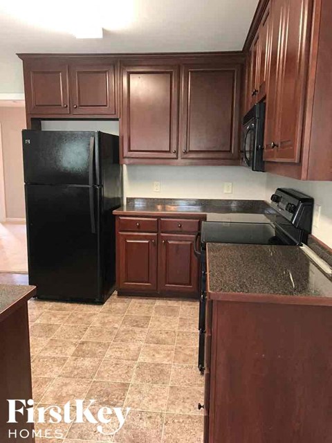 a kitchen with dark wood cabinets and a black refrigerator