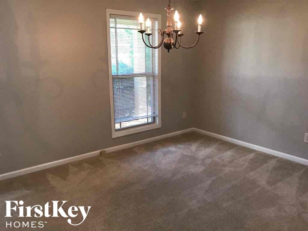 a empty dining room with a chandelier and a window