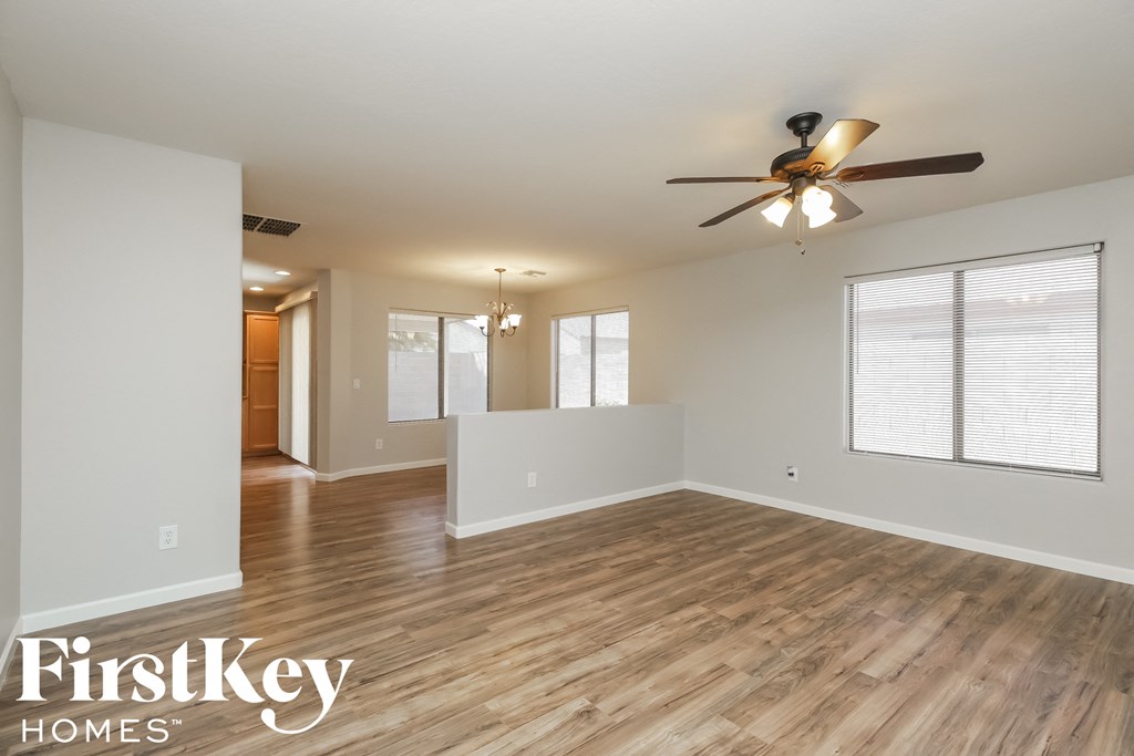 the living room and dining room of an empty house with a ceiling fan