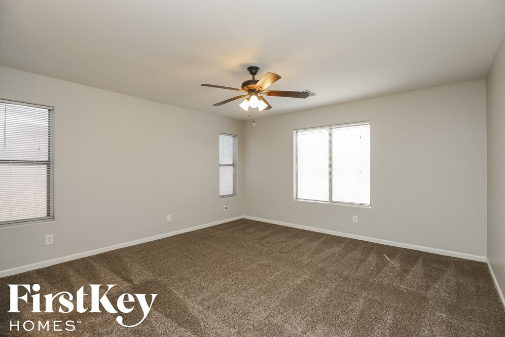 the spacious living room with carpeting and a ceiling fan