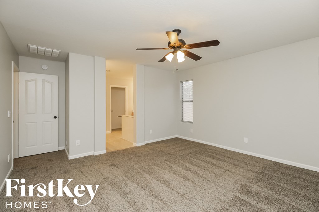 an empty living room with a ceiling fan and a carpet