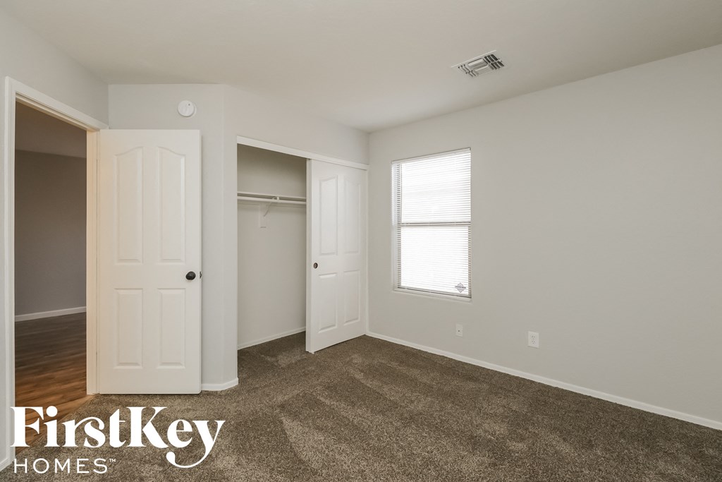 a bedroom with a closet and a window and a carpeted floor