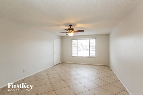 A spacious room with a ceiling fan and a window with blinds.