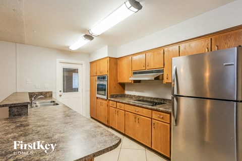 A kitchen with wooden cabinets and a stainless steel refrigerator.