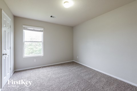 a bedroom with white carpet and a window