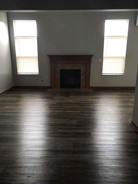 an empty living room with wood floors and a fireplace