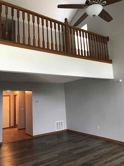 an empty living room with a ceiling fan and a staircase