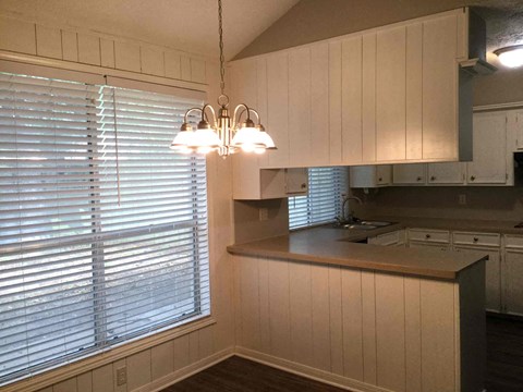 a kitchen with white cabinets and a large window