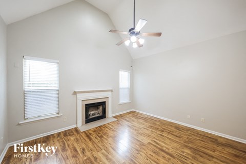 A spacious room with a fireplace and a ceiling fan.