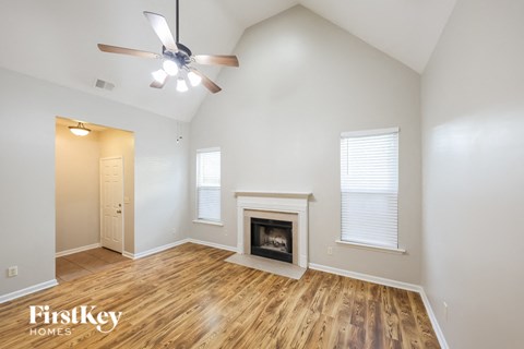 A spacious room with a fireplace and a ceiling fan.