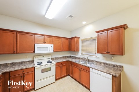 A kitchen with wooden cabinets and a white stove top oven.