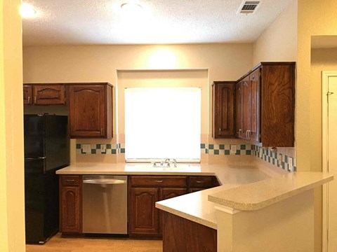 A kitchen with wooden cabinets and a black refrigerator.