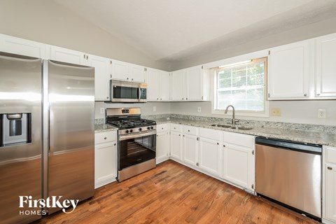 A kitchen with white cabinets and a stainless steel refrigerator.