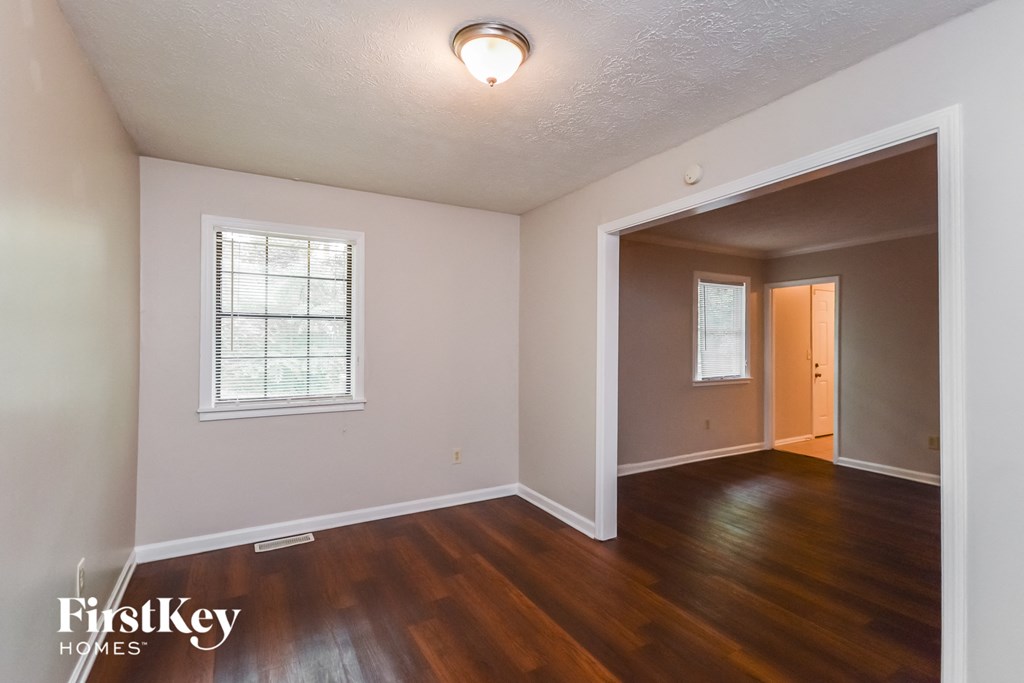 the living room of an empty house with wood floors and a door to a hallway