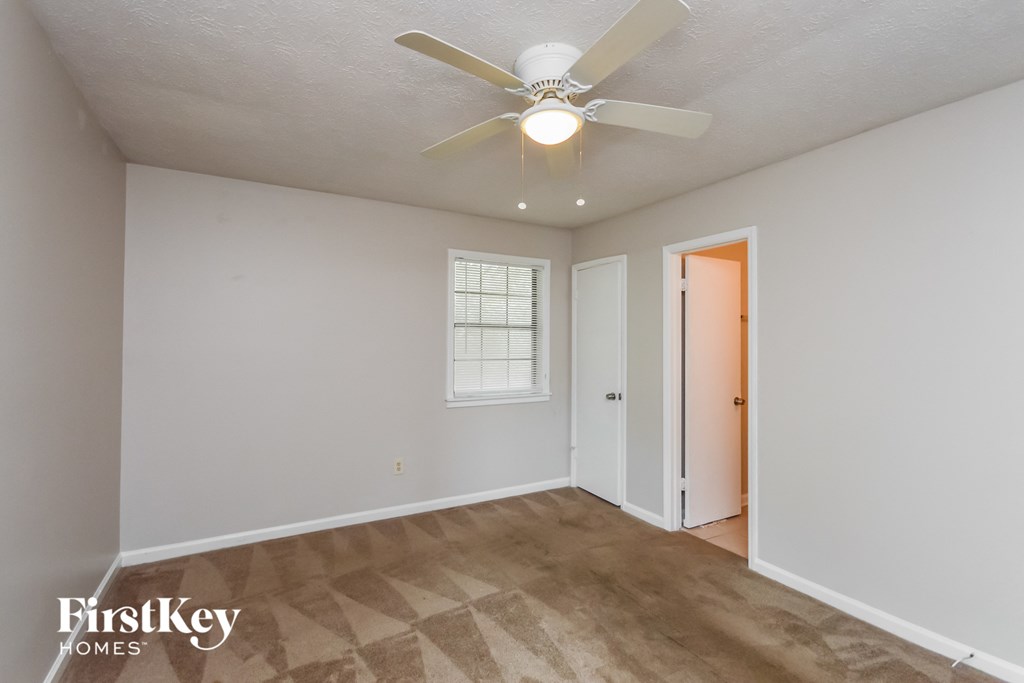a living room with a ceiling fan and a door to a closet