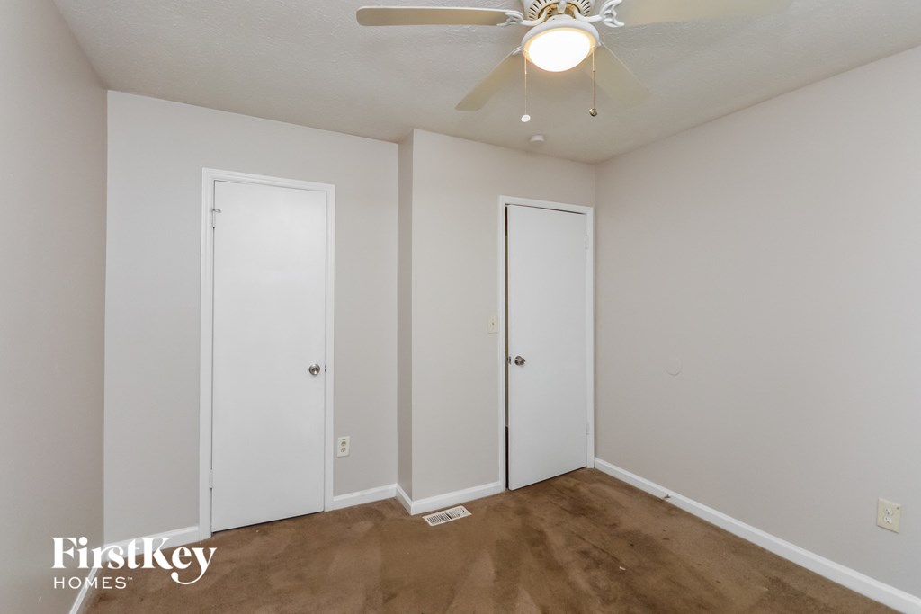a bedroom with a ceiling fan and two doors