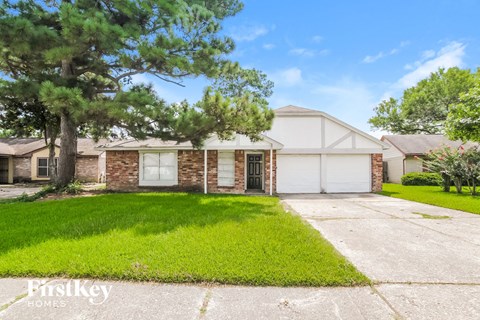 a white and brick house with a lawn in front of it