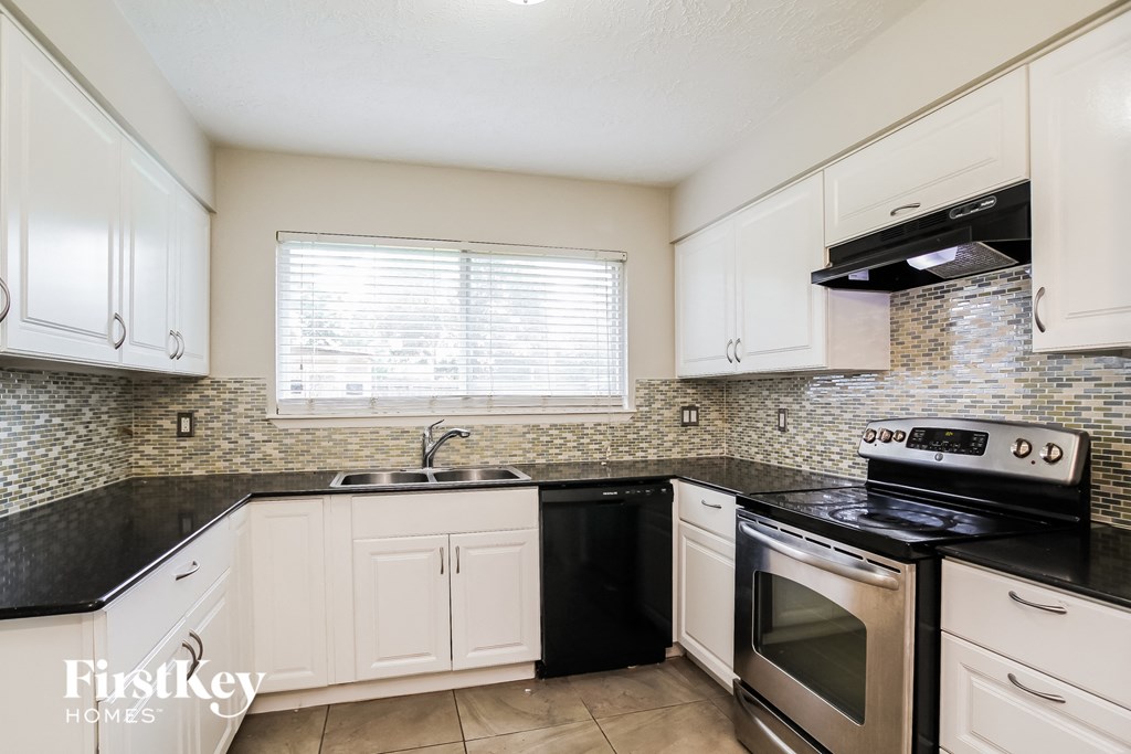 a kitchen with white cabinets and black counter tops