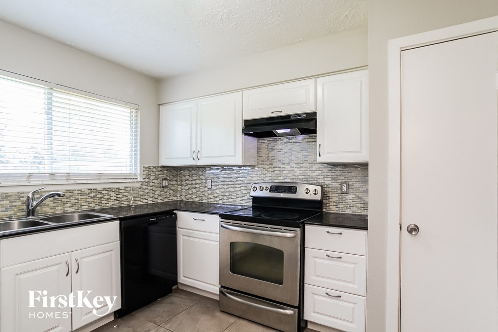 a kitchen with white cabinets and black and stainless steel appliances
