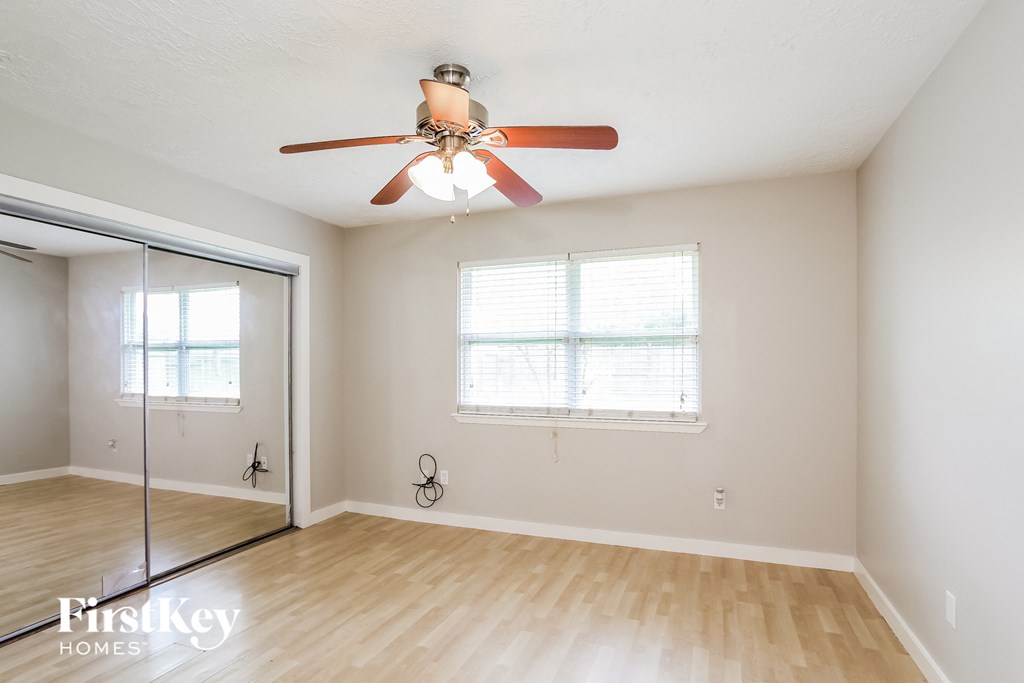 a living room with a ceiling fan and a mirrored closet