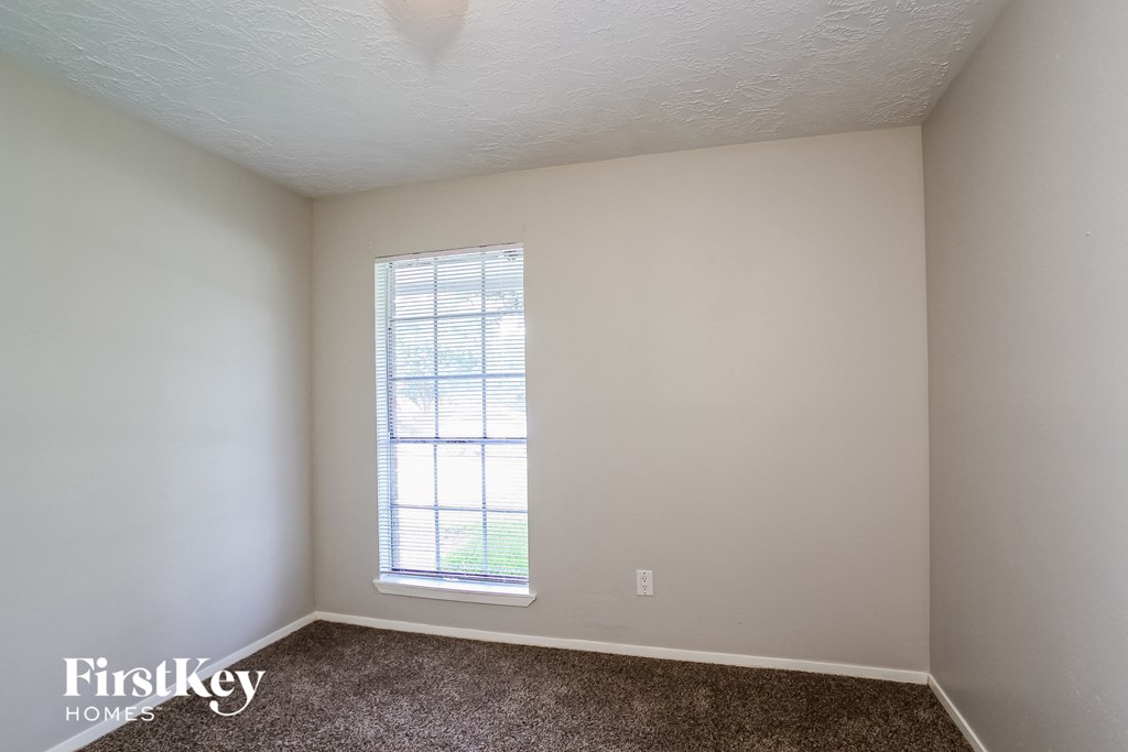 a bedroom with white walls and a window