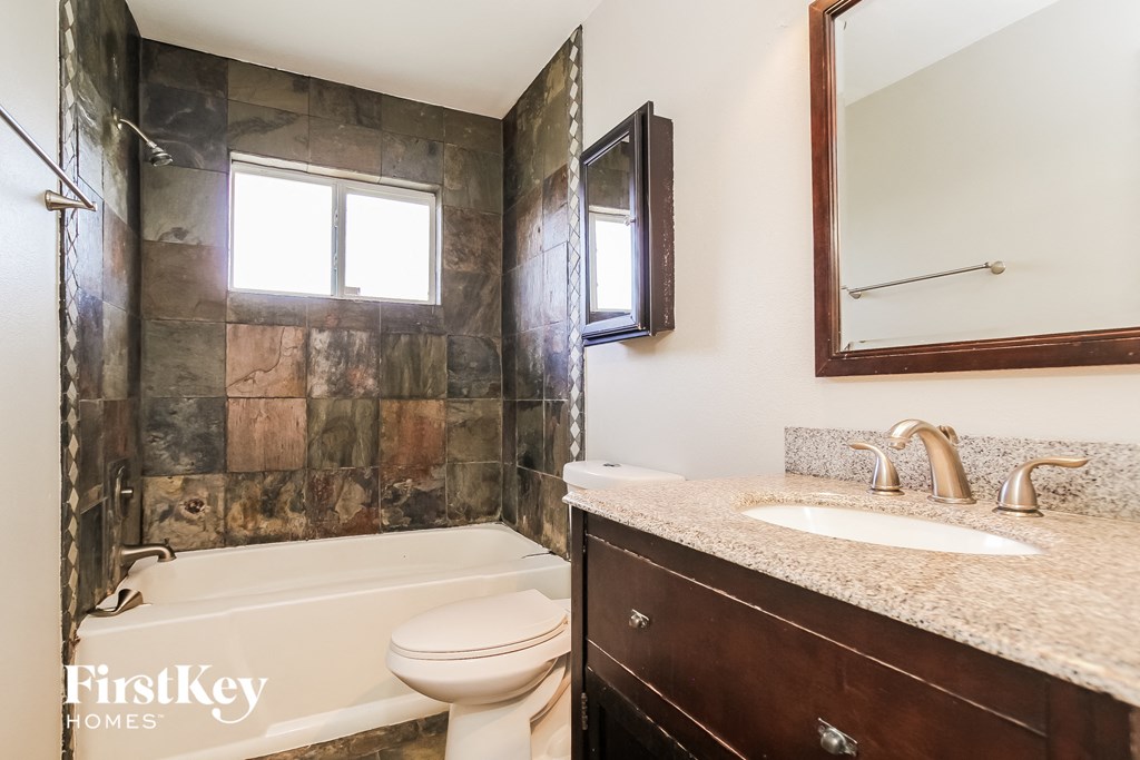 a bathroom with a tub sink and toilet and a mirror