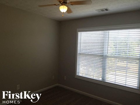 A room with a ceiling fan and a window with blinds.