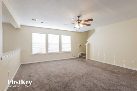 a living room with carpet and a ceiling fan