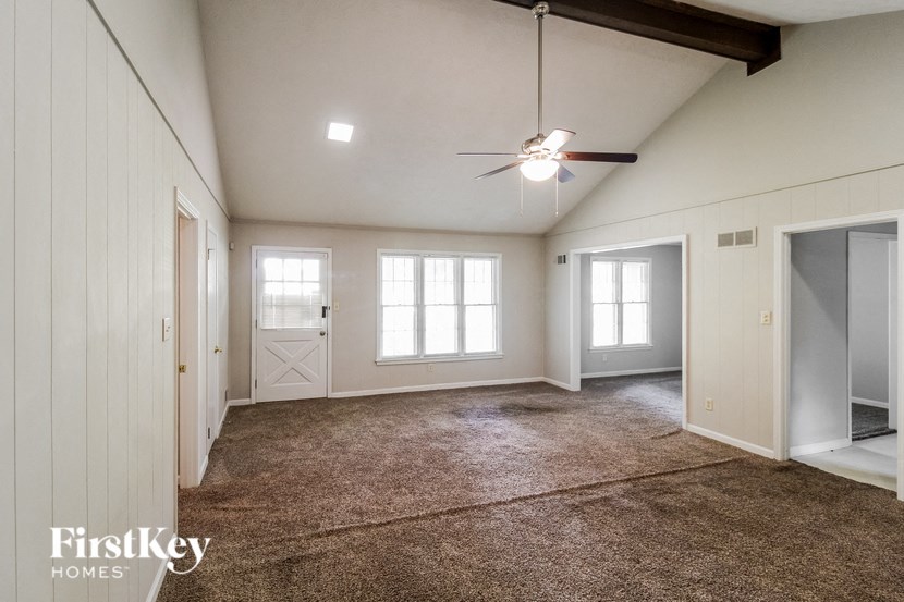 an empty living room with white walls and a ceiling fan