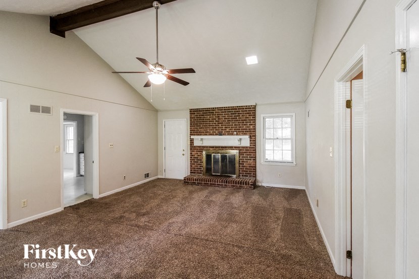 an empty living room with a fireplace and a ceiling fan