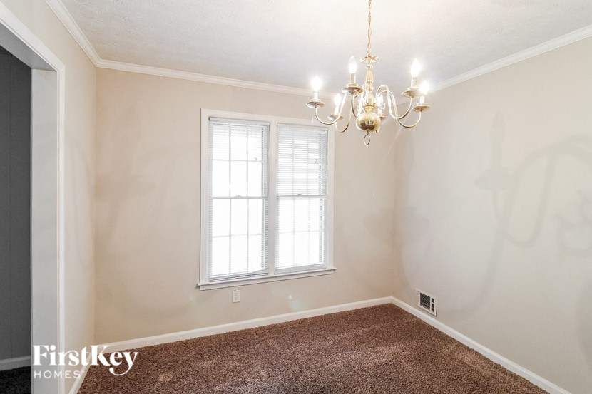 an empty living room with a window and a chandelier