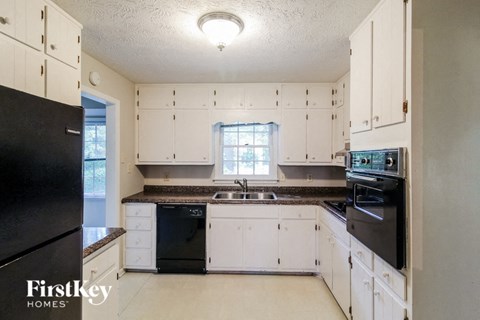 a white kitchen with black appliances and white cabinets