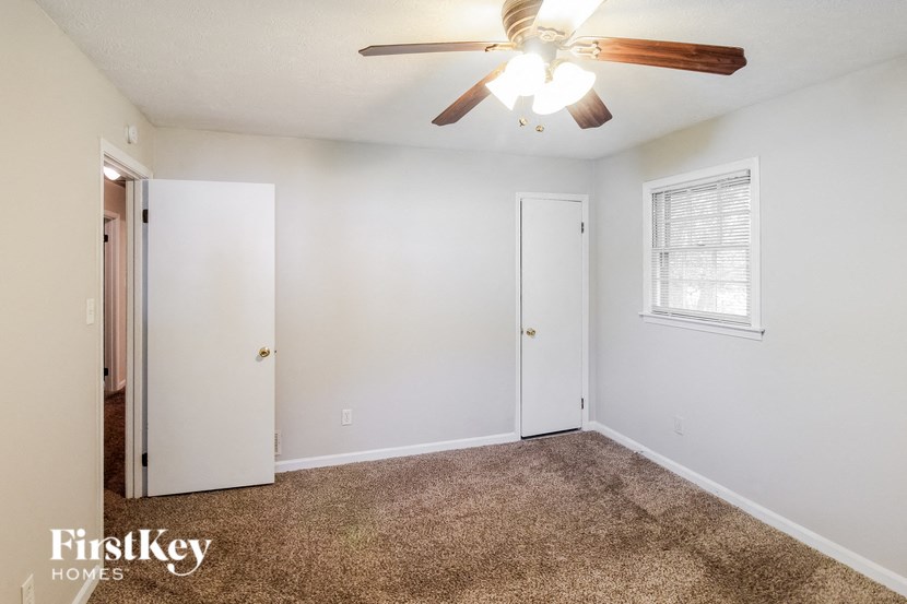 a bedroom with a ceiling fan and a door to a closet