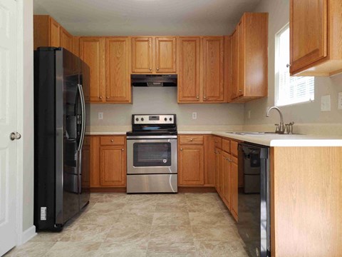 A kitchen with wooden cabinets and a black refrigerator.