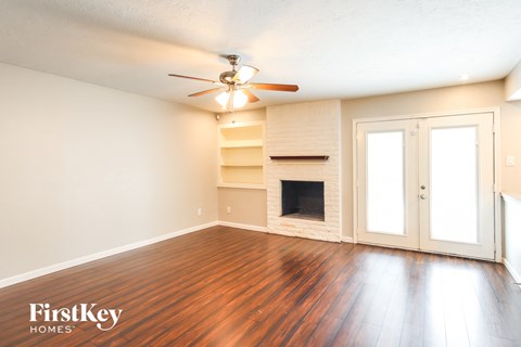 an empty living room with a fireplace and a ceiling fan