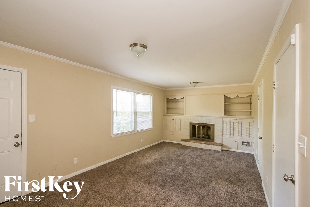a carpeted living room with a fireplace and a window