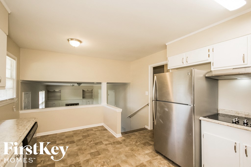 an empty kitchen with stainless steel appliances and white cabinets