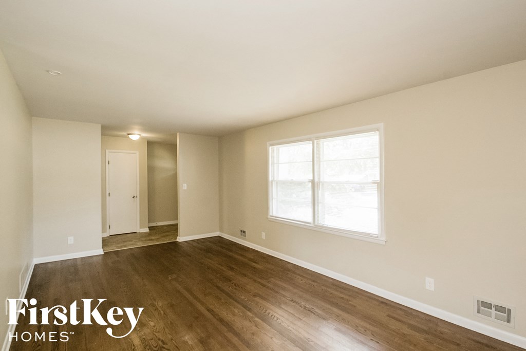 the spacious living room with wood flooring and a large window