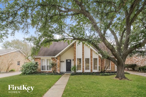 A brick house with a tree in front of it.
