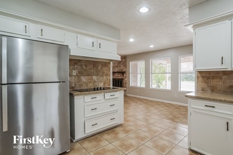 A kitchen with a stainless steel refrigerator and white cabinets.